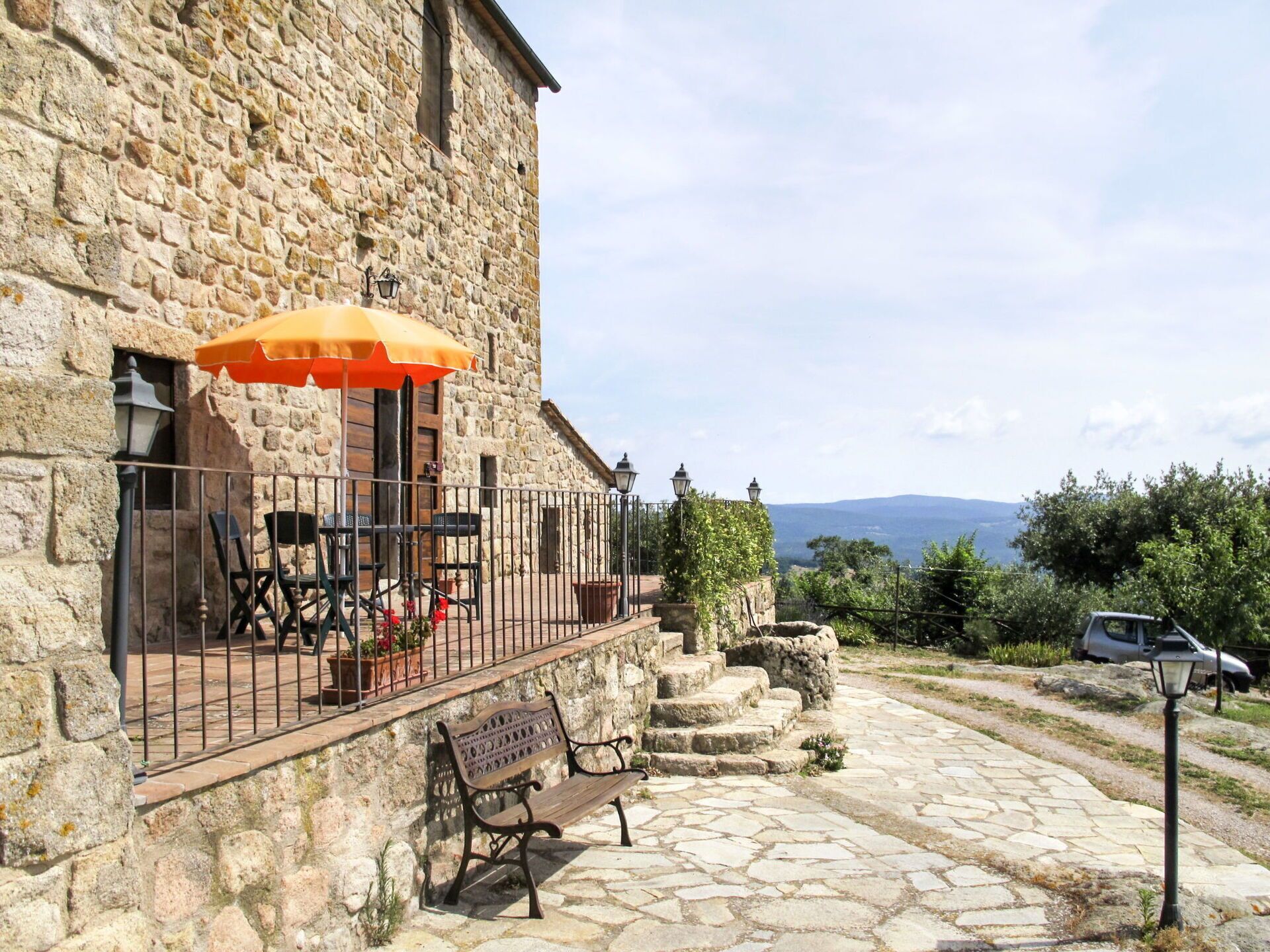 A stone building with a balcony, outdoor seating, and a view of the landscape.
