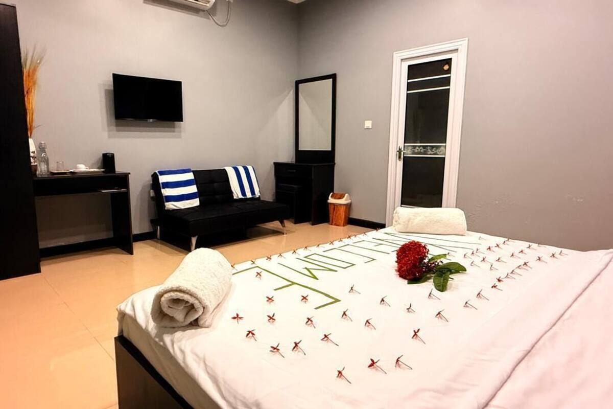 Ein Schlafzimmer mit Bett, Fernseher, Spiegel, Schreibtisch und Kleiderschrank.