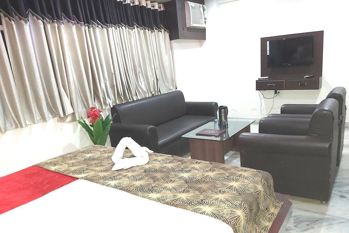 Ein Hotelzimmer mit Bett, Sofa, Couchtisch und Fernseher.