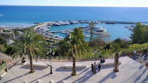 Ein Yachthafen mit Booten, ein Strand und eine Promenade mit Palmen.