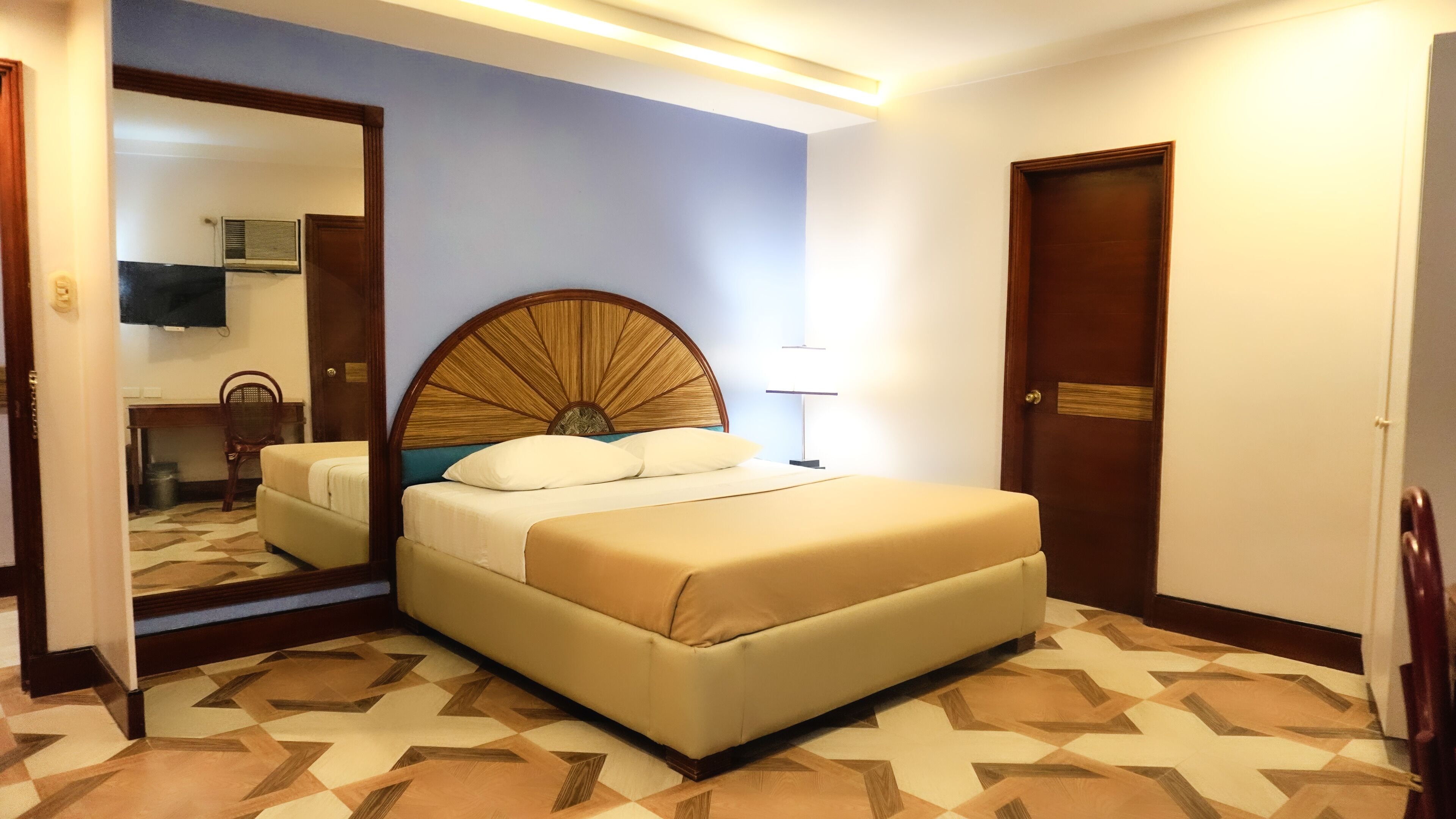 Habitación de hotel con una cama grande, un espejo, un escritorio y una silla.