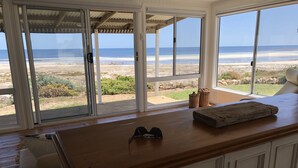 Una habitación con una encimera de madera, un par de gafas de sol y vistas a la playa a través de amplias ventanas.