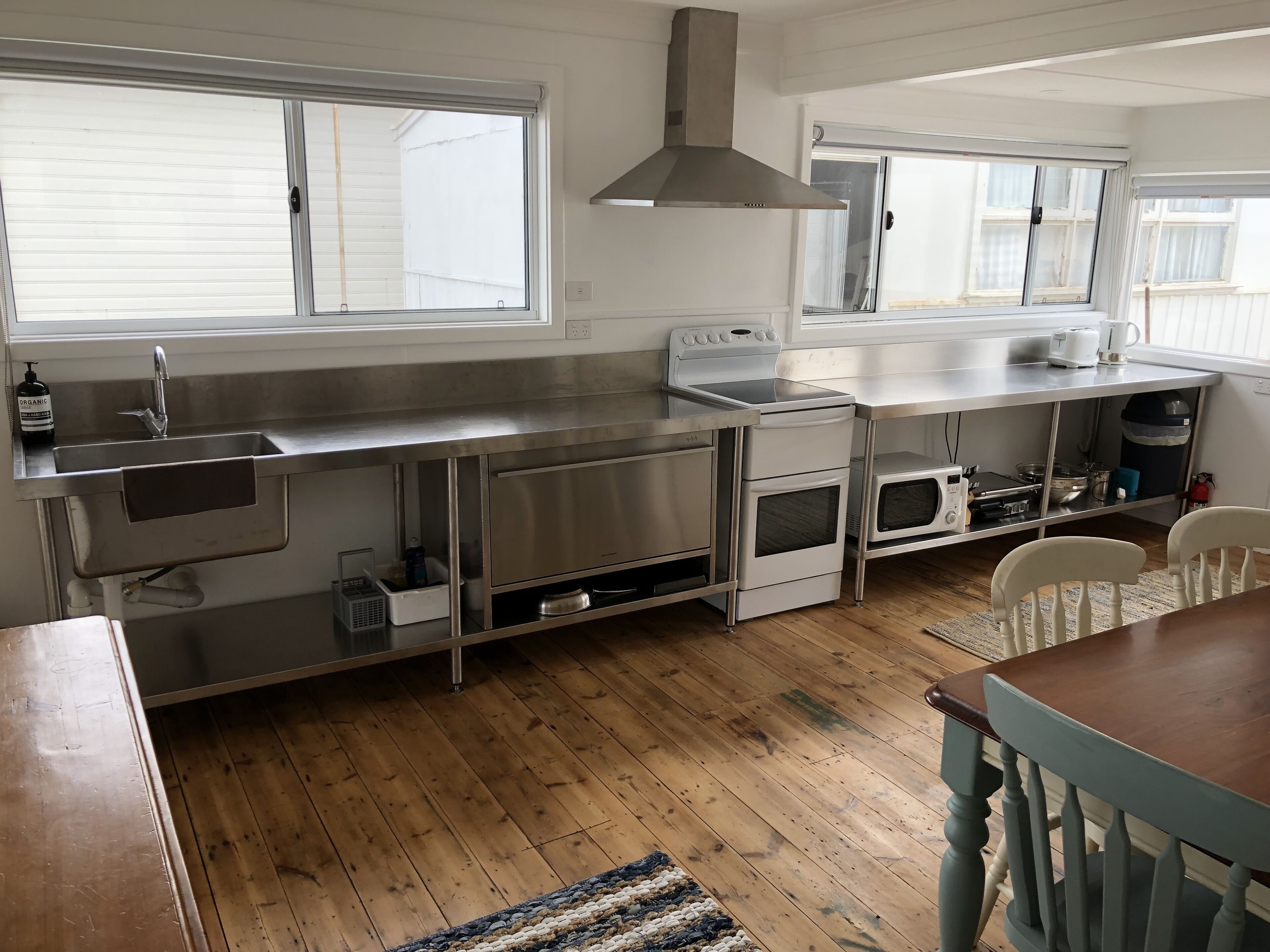 Een moderne keuken met roestvrijstalen apparatuur, een inbouwoven en een groot raam dat zorgt voor natuurlijk licht.