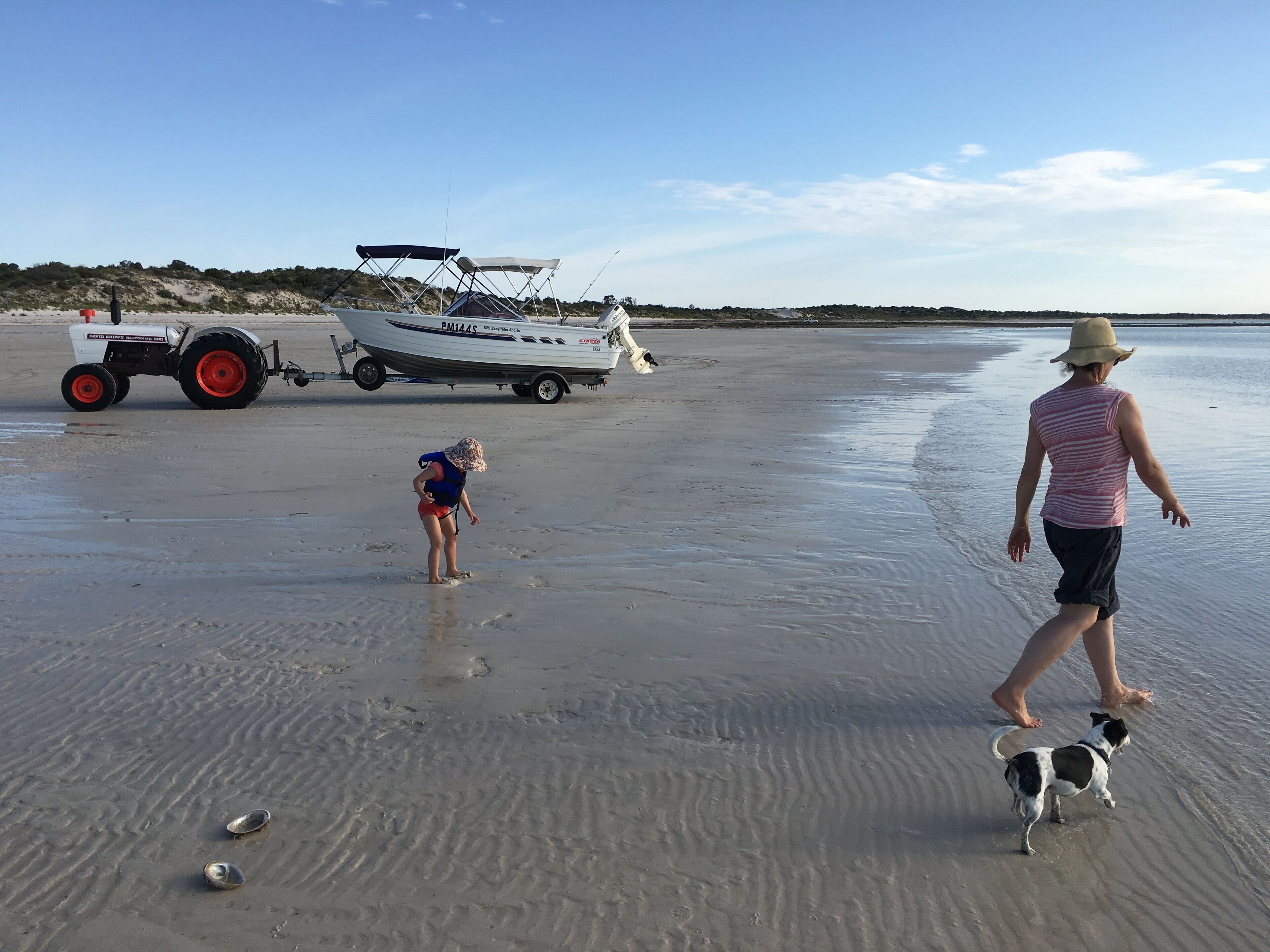 En strand med en campingvogn og en båd i baggrunden.