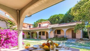 An outdoor dining area with a table set for two, surrounded by a courtyard with a building in the background. - Nice apartment for 6 people with A/C, pool, WIFI, TV and terrace (Scarlino)