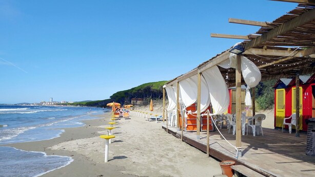 A beachside hotel with a wooden deck, beach chairs, and umbrellas. - Nice apartment for 6 people with A/C, pool, WIFI, TV and terrace (Scarlino)