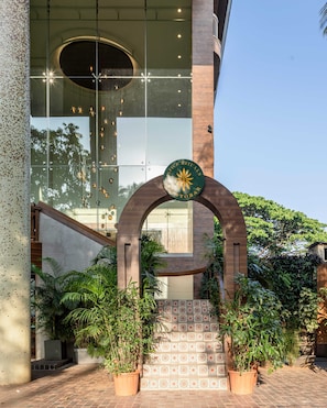 A building entrance with a glass facade, a wooden archway, and potted plants. - YU Hotel Candolim (Candolim)