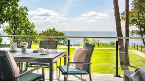 Una terraza con una mesa lista para dos personas, con vistas a un área verde y al mar.