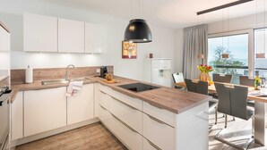 Una cocina moderna con armarios blancos, encimera de madera y una isla grande con un lavamanos.