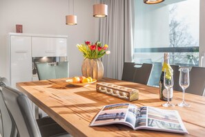 Ein Holztisch mit einer Blumenvase in Rot und Gelb, einer Champagnerflasche und zwei Gläsern.