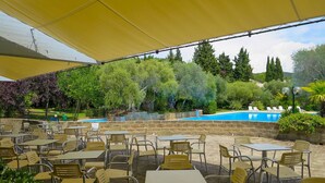 An outdoor patio with tables and chairs, a swimming pool, and surrounding greenery. - Nice apartment in villa for 6 people with WIFI, A/C, pool, TV, terrace and pets allowed (Castiglione Della Pescaia)