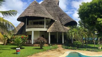 Una casa con tejados de paja y piscina.