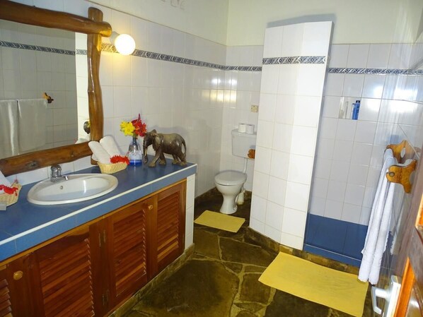 A bathroom with a sink, mirror, toilet, and wooden cabinets. - Diani Paradise Villas (Diani Beach)