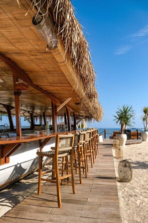 A beachside bar with wooden chairs and a thatched roof. - Ama-Lurra Villa (Gili Air)