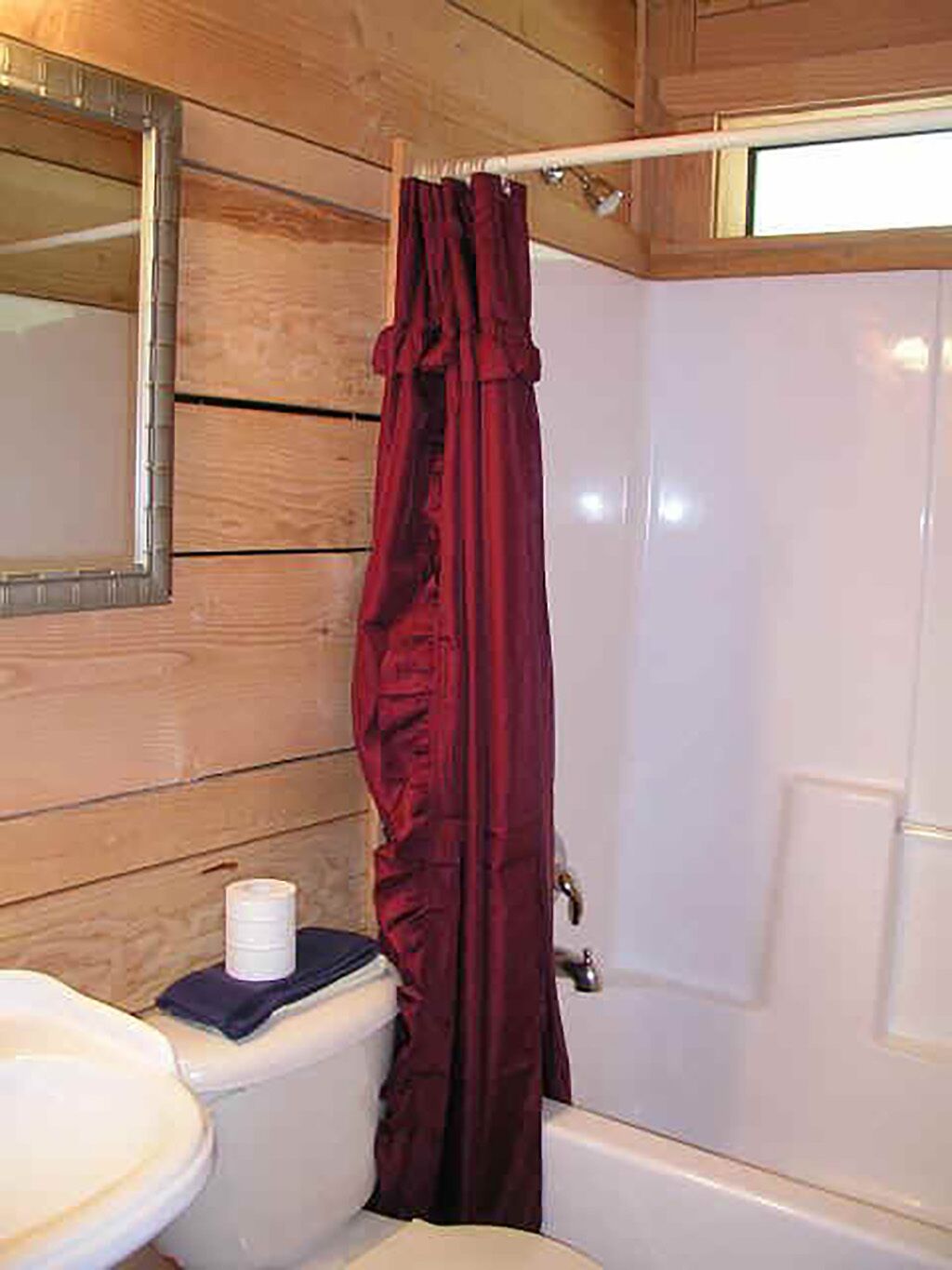 A wooden-paneled bathroom with a toilet, sink, and bathtub.
