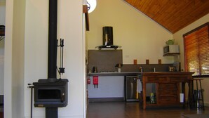 Una cocina moderna con estufa de leña, lavavajillas de acero inoxidable y mesa de comedor de madera.