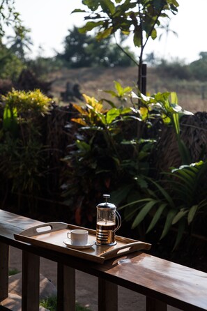 A wooden table with a tray holding a white cup and a glass of coffee. - Artist Cottages (Morjim)