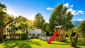 Une maison avec un toboggan rouge, une piscine et une pelouse bien entretenue.