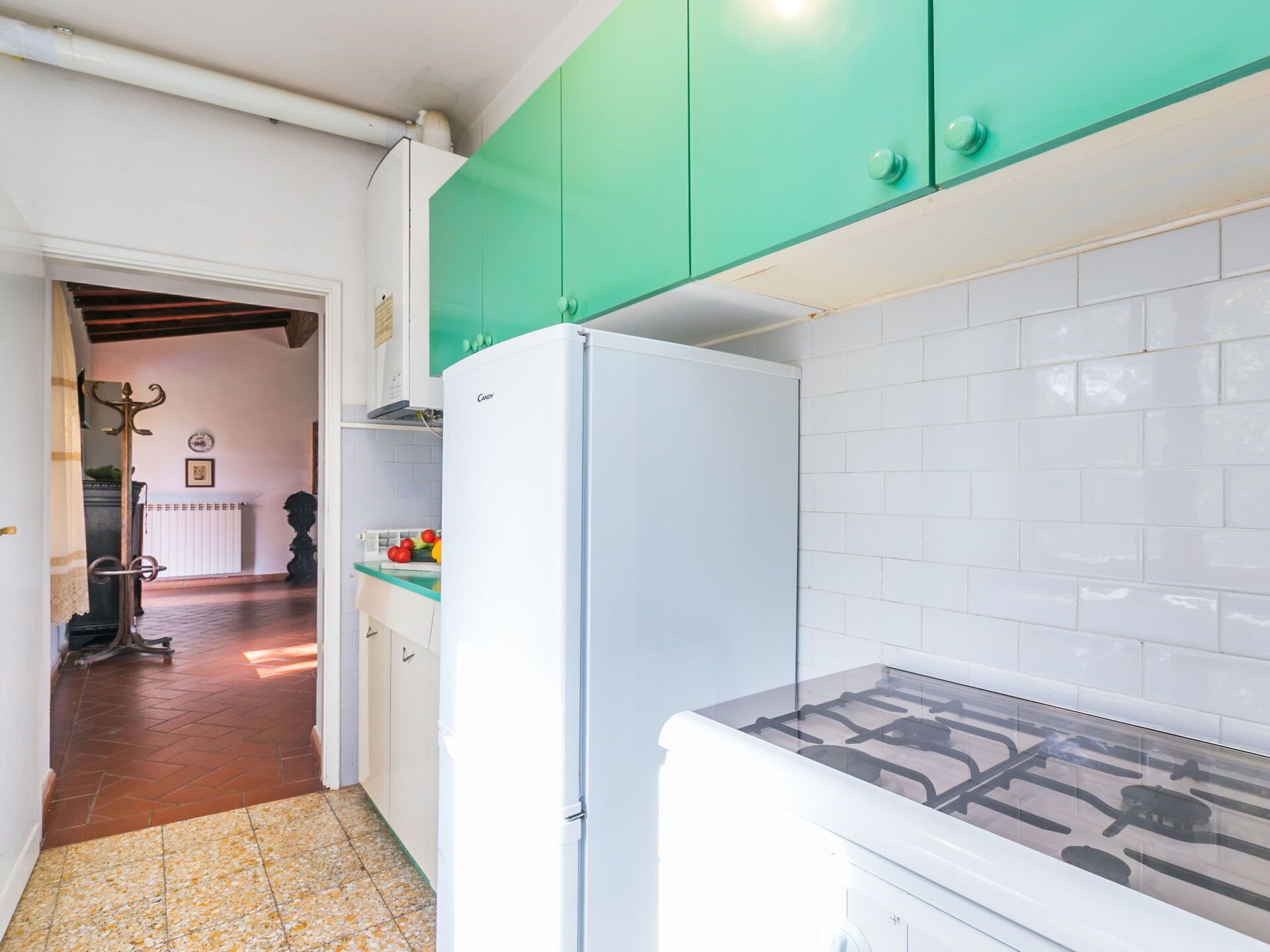 A kitchen with a white refrigerator, green cabinets, and a tiled backsplash.