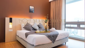 A modern hotel room with a large bed, a bedside table, a nightstand, a window with curtains, and a city view. - Swiss Garden Residence Kuala Lumpur (Kuala Lumpur)