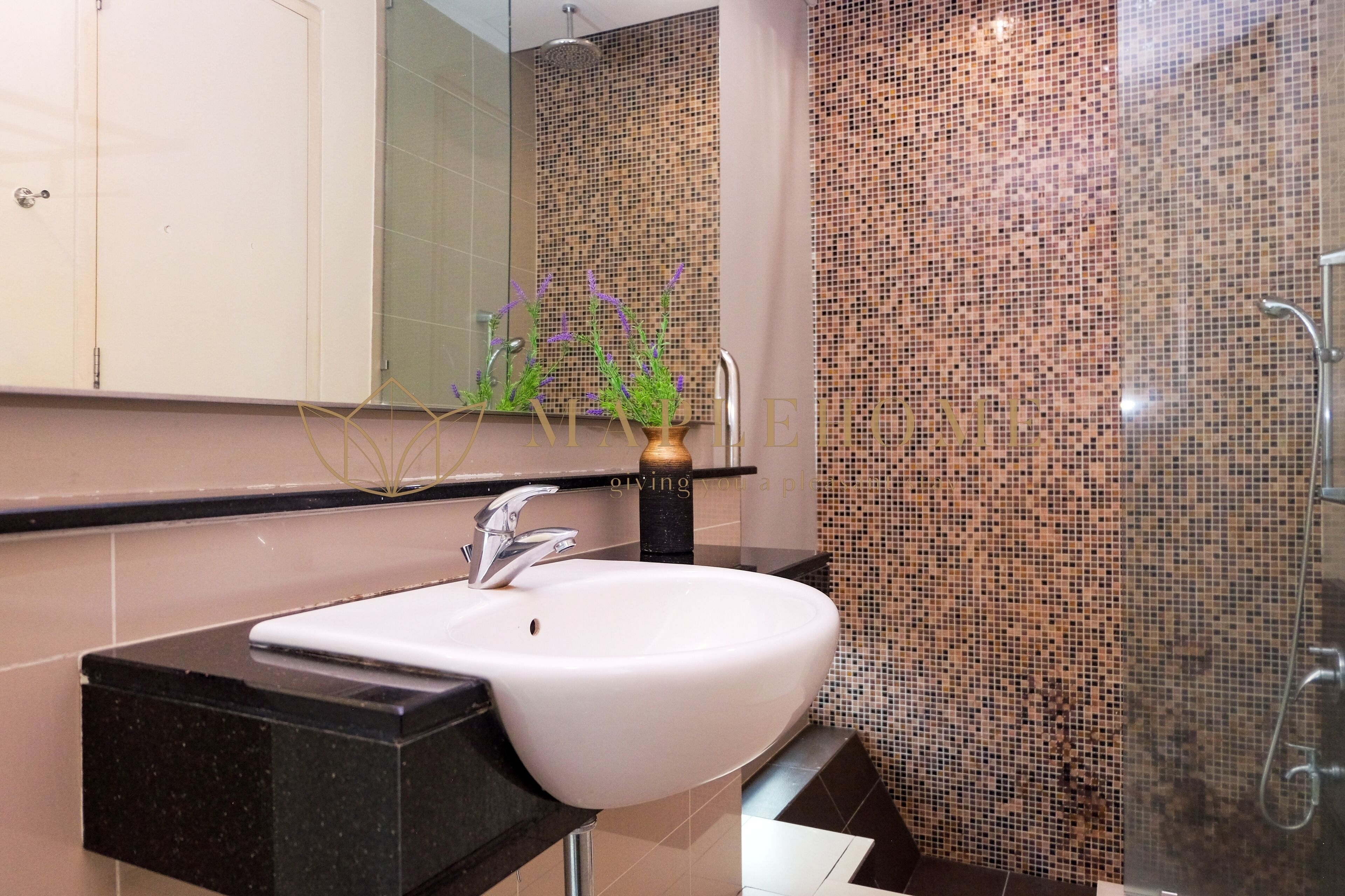 A bathroom with a white sink, a mirror, and a shower area with mosaic tiles.