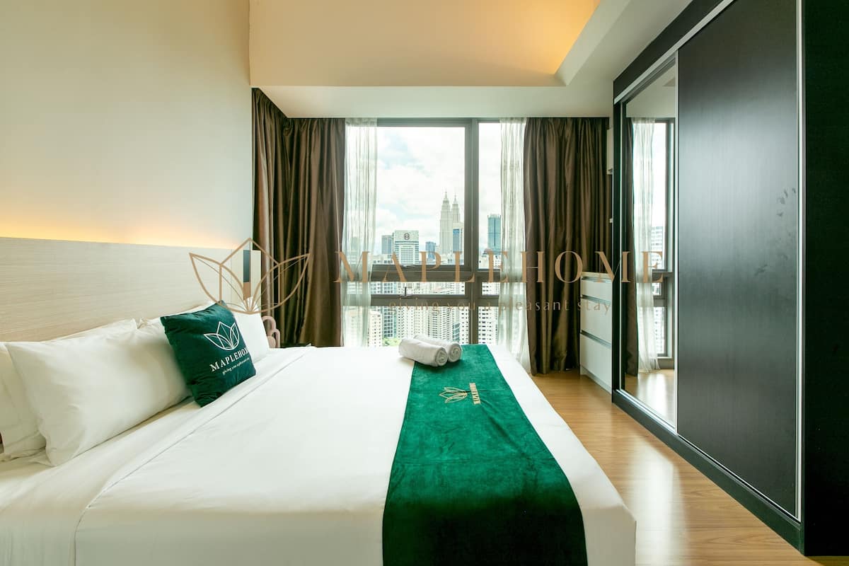 Una habitación de hotel con una cama, un plaid verde y vistas a la ciudad.