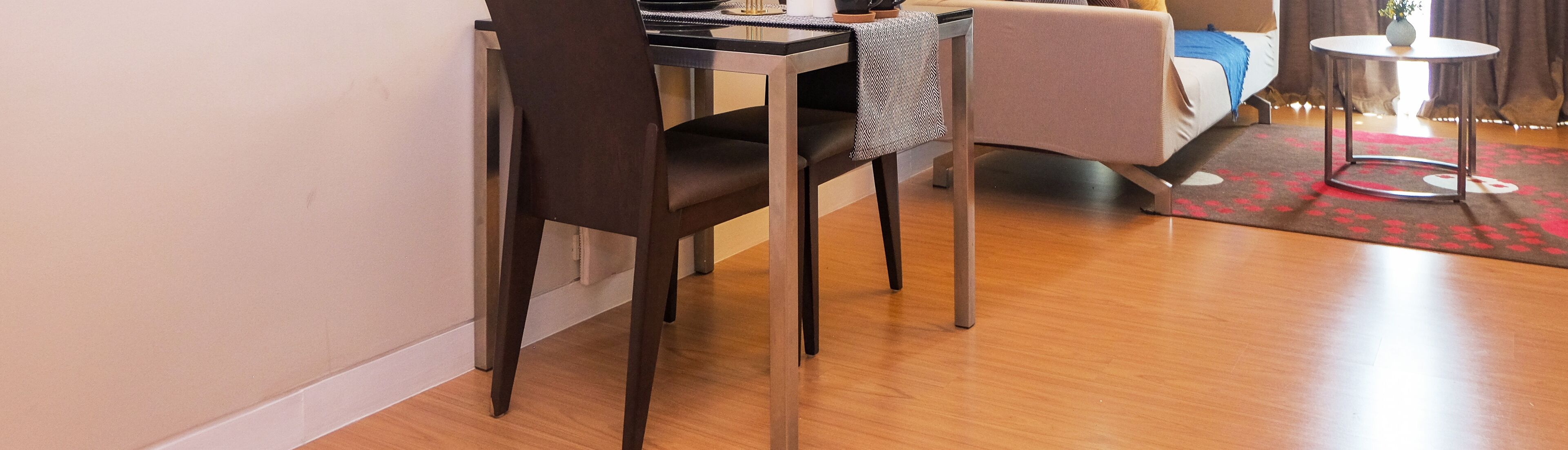 Een moderne woonkamer met een donker houten stoel, een klein rond tafeltje en een bank.
