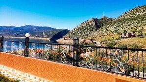 Vista costera con barandilla metálica y cielo azul despejado.