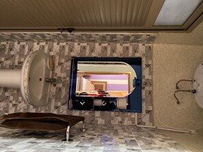 Ein Badezimmer mit Marmorboden, einem großen Spiegel, einer Badewanne und einer Toilette.