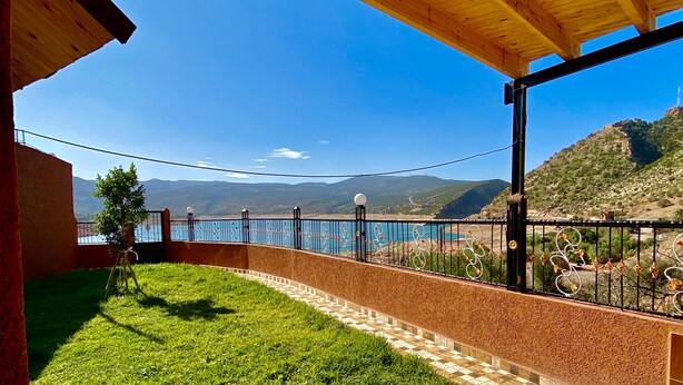 Un espacio al aire libre techado con vistas a un lago y montañas.