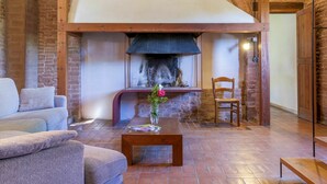 A cozy living room with a fireplace, a sofa, a wooden coffee table, and a chair. - Apartment in villa with private pool, WIFI, hot tub, A/C, TV, patio, pets allowed, panoramic view (Castiglione Del Lago)
