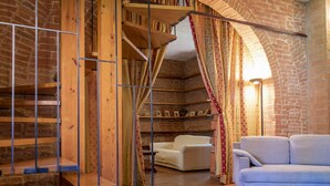A rustic interior with exposed brick walls, a wooden staircase, a sofa, and a chair. - Apartment in villa with private pool, WIFI, hot tub, A/C, TV, patio, pets allowed, panoramic view (Castiglione Del Lago)