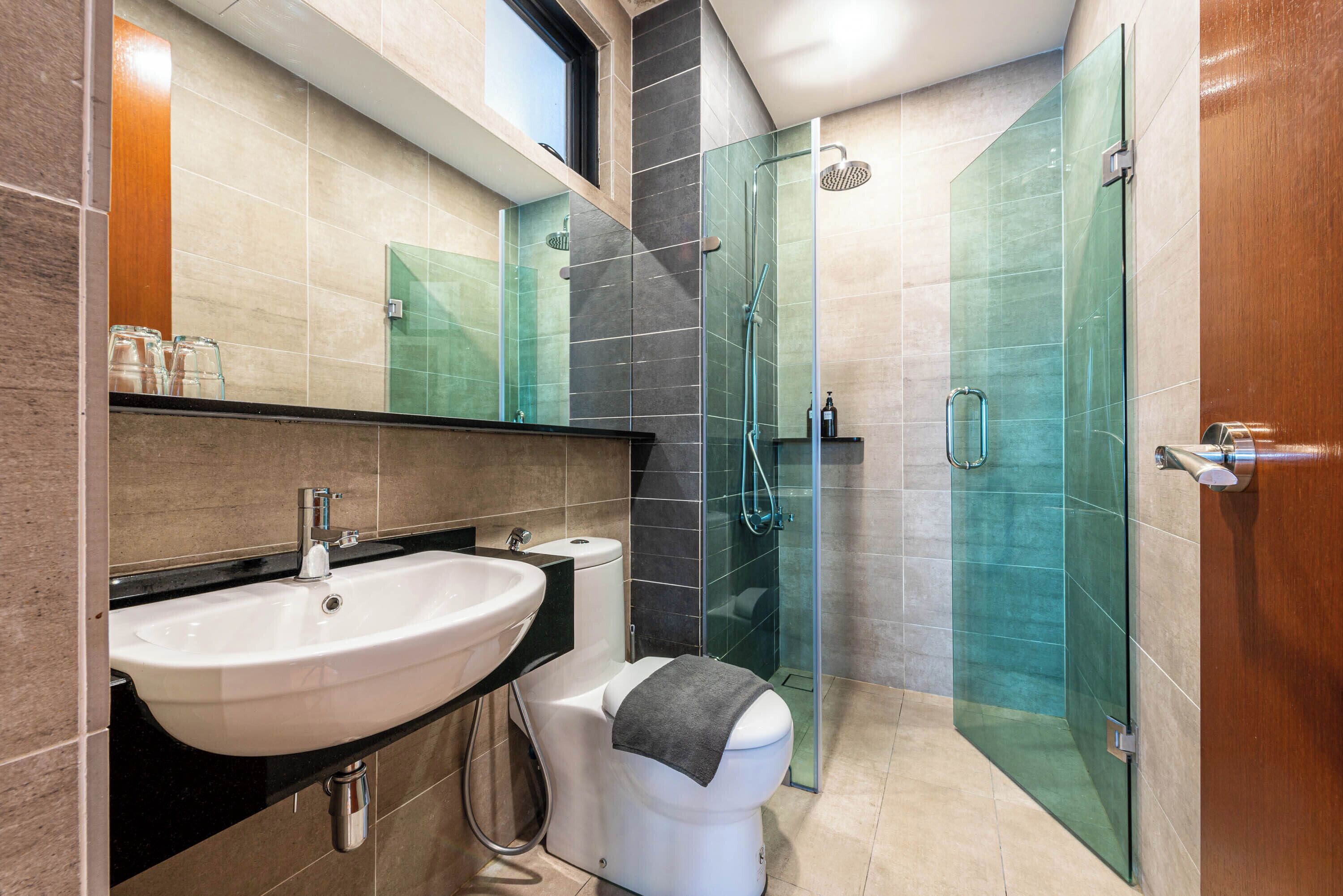 A modern bathroom with a white sink, a glass shower enclosure, and a toilet.
