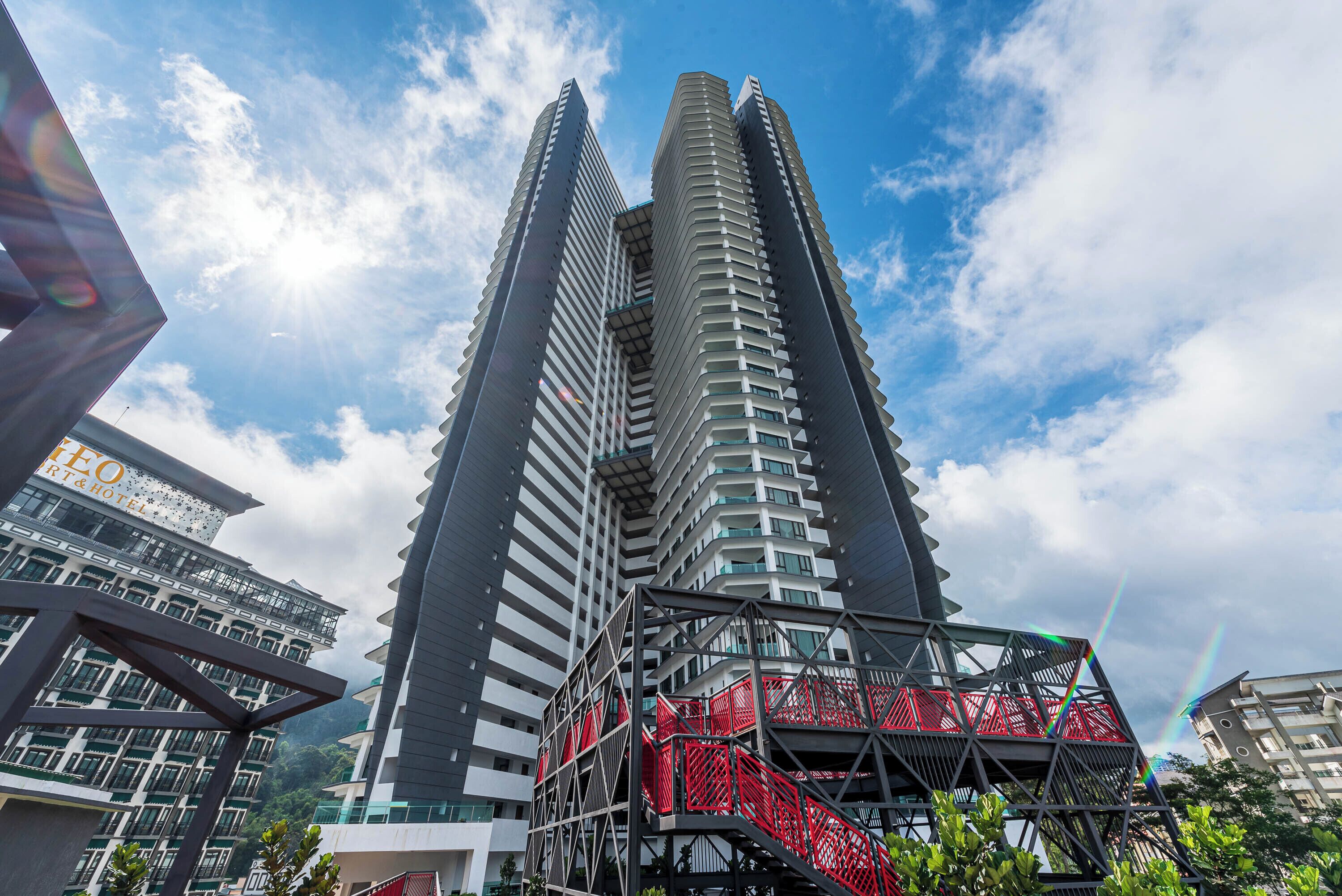 A high-rise building with multiple floors and balconies, surrounded by other buildings.
