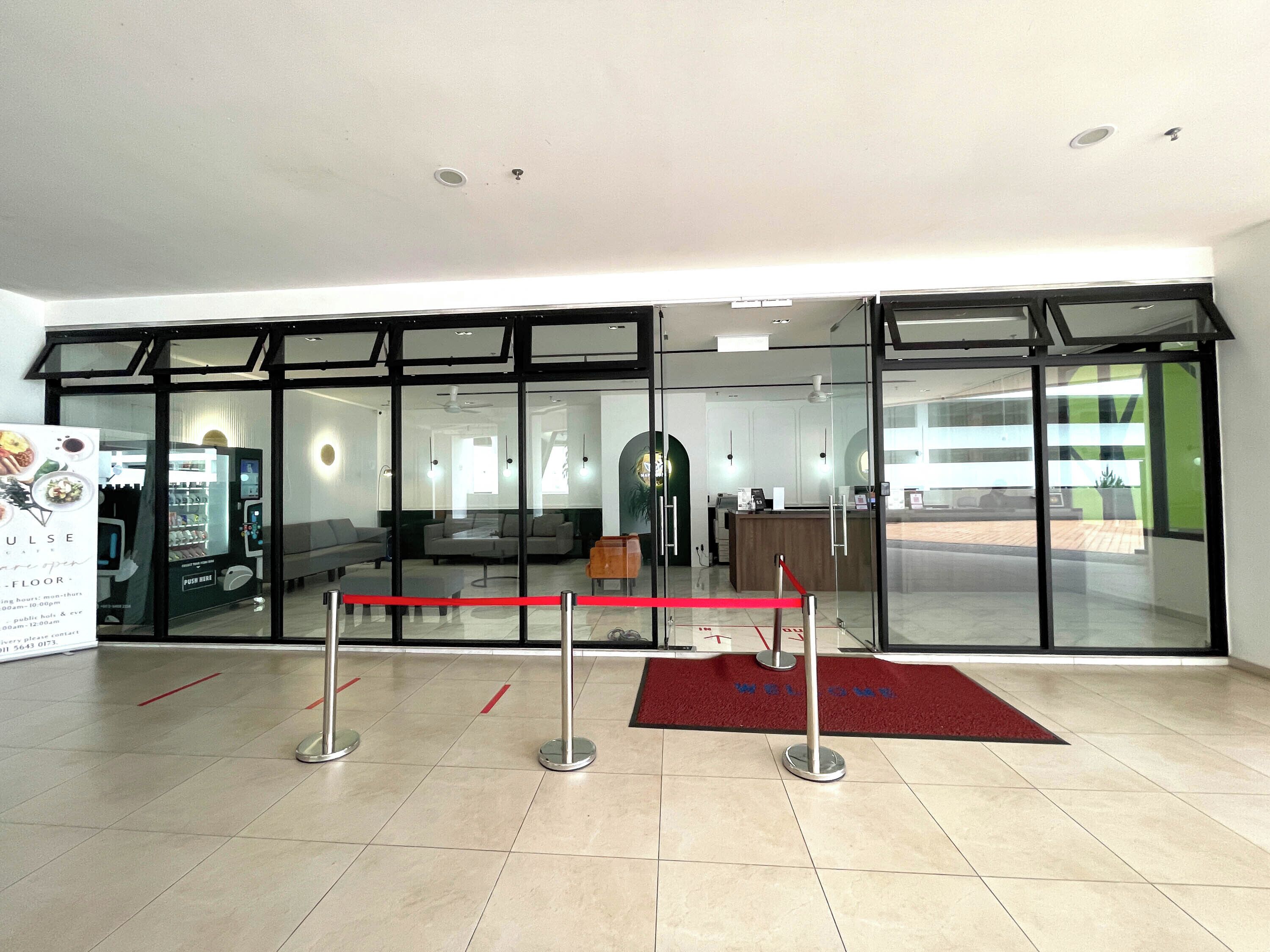 Un vestíbul d'hotel modern amb una taquilla d'admissió, zona de seients i màquina expenedora.