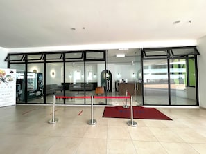 Um lobby moderno de hotel com balcão de recepção, área de estar e máquina de venda automática.