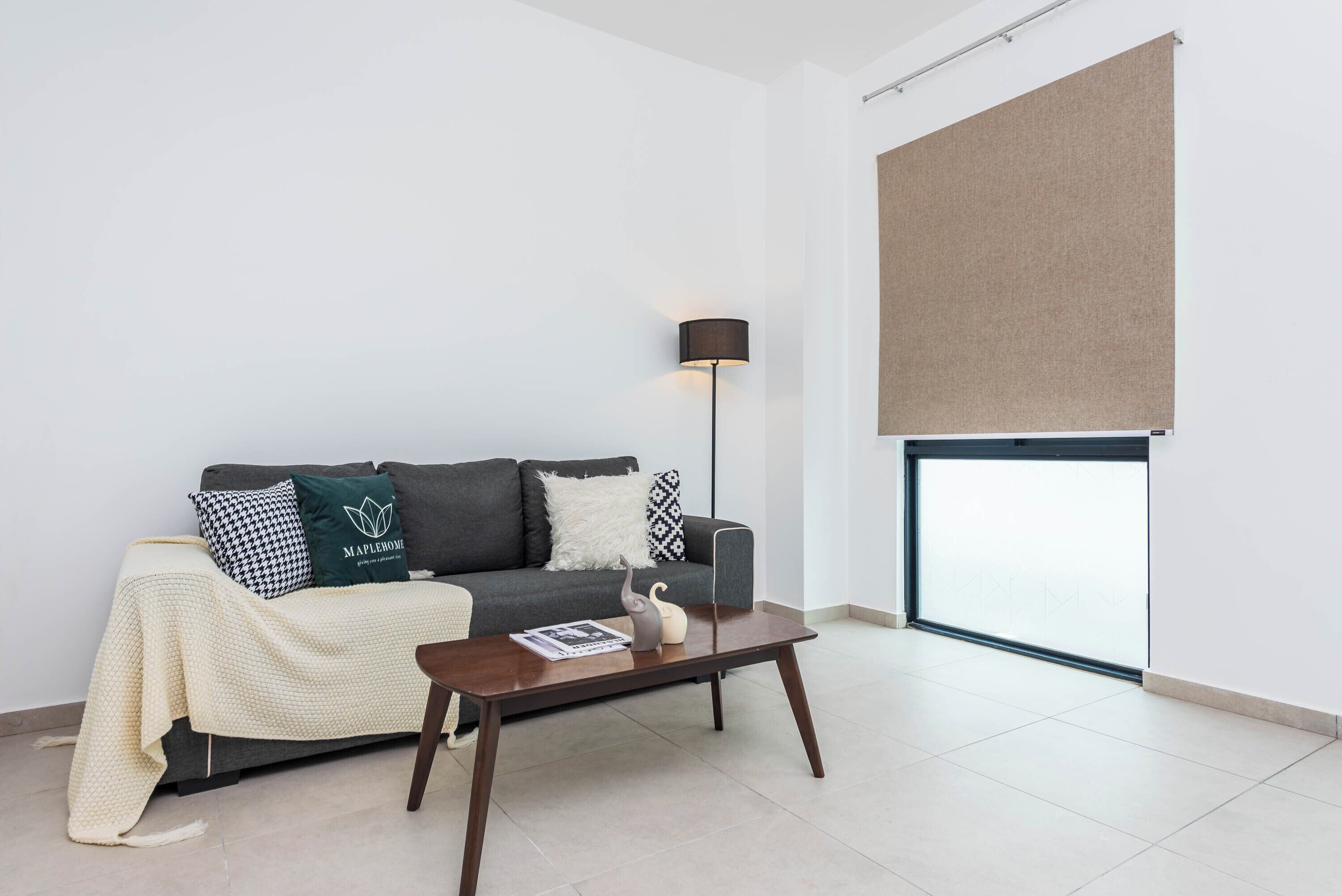 A modern living room with a grey sofa, a coffee table, and a floor lamp.