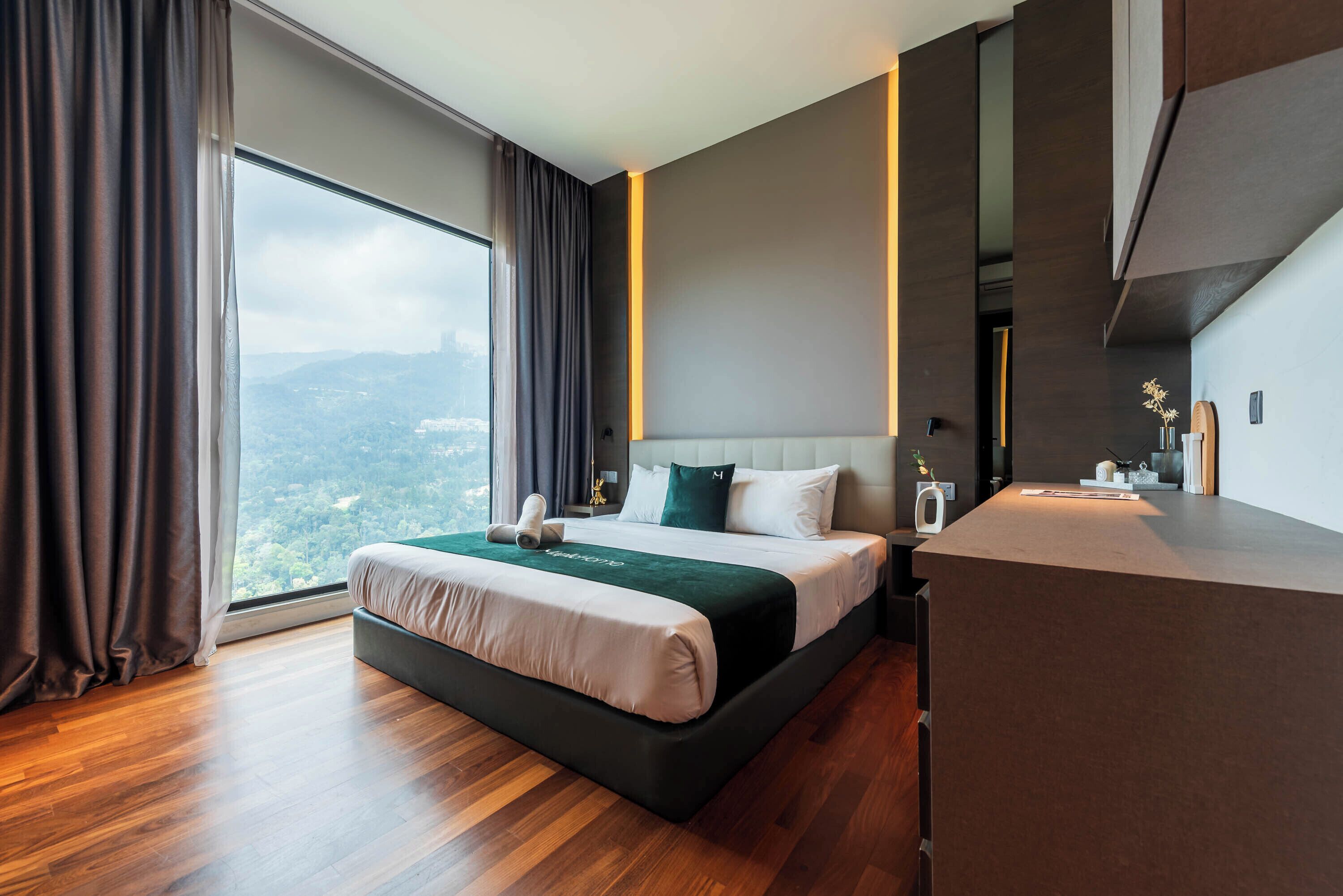 A modern hotel room with a large bed, a desk, and a view of the city.