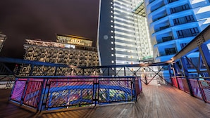 A hotel with a prominent sign, a modern building with blue lighting, and a wooden deck with colorful railings. - Geo38 Premier Suites Genting Highlands (Genting Highlands)