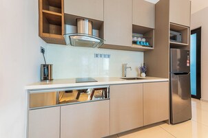 A modern kitchen with built-in appliances, a stainless steel refrigerator, and a microwave.