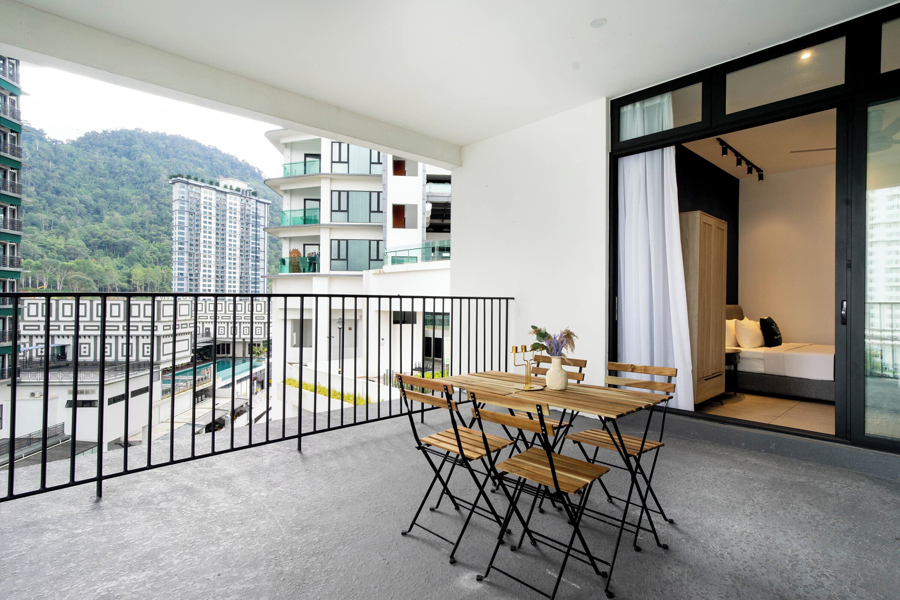 Un balcon avec une table et des chaises en bois, une vue sur une montagne et un immeuble doté de balcons.