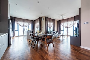 A spacious living area with a dining table, sofas, and a kitchen area.