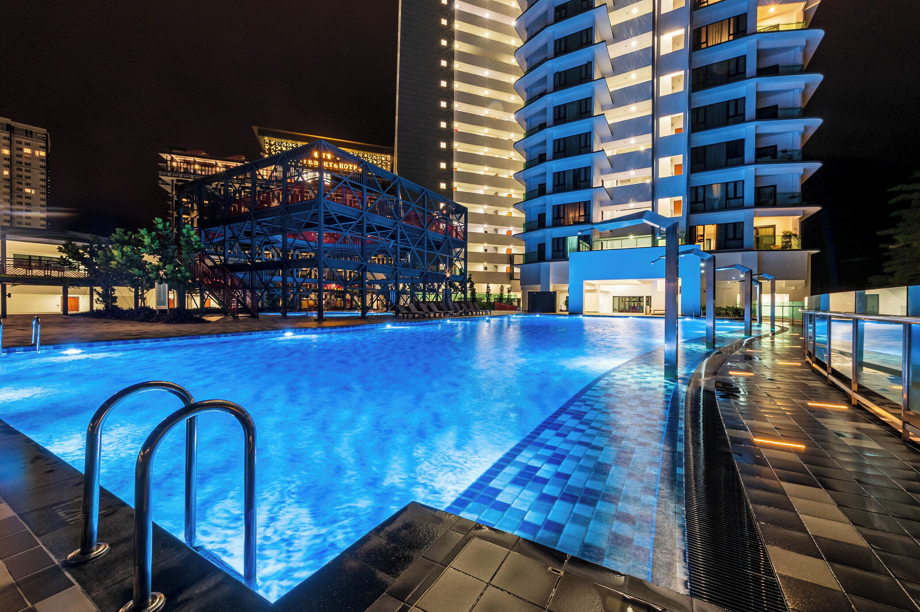 A swimming pool with a modern design, surrounded by a high-rise building with multiple balconies.