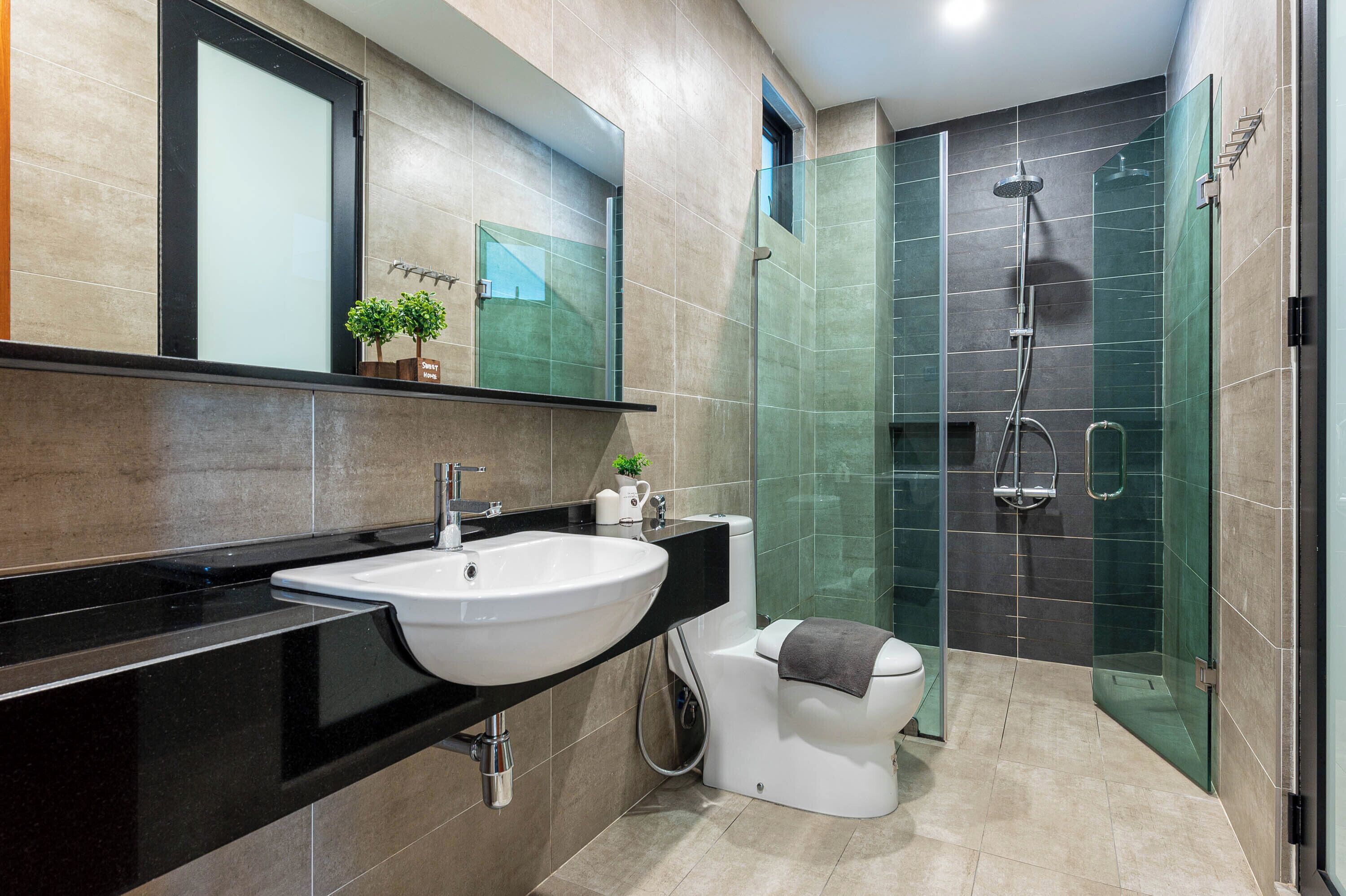 A modern bathroom with a large sink, toilet, and glass-enclosed shower area.