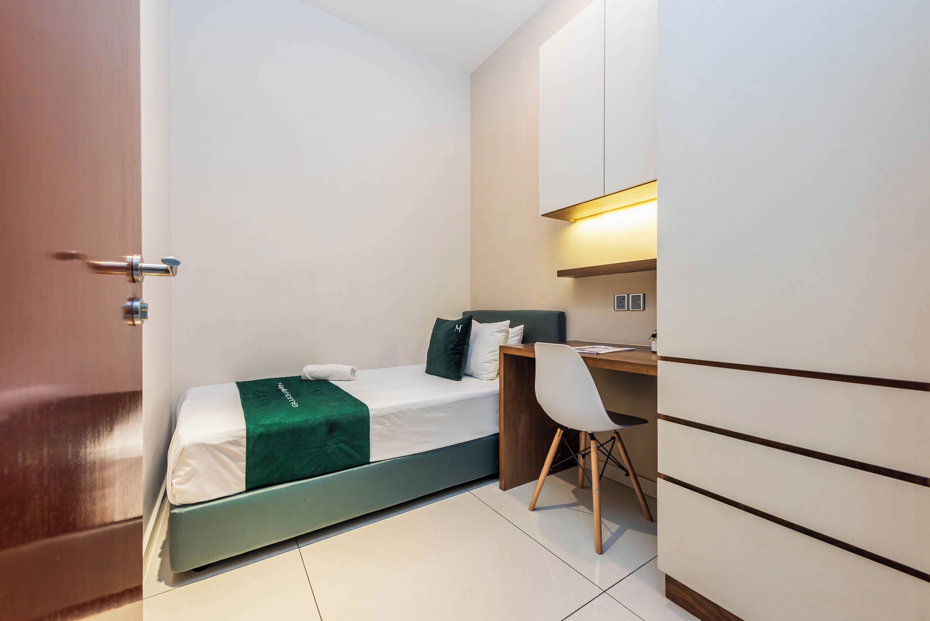 A compact bedroom with a bed, a desk, and a chair.