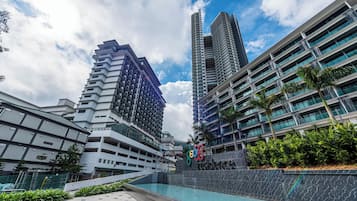 Een modern hotel met een zwembad, hoge gebouwen en een heldere lucht.