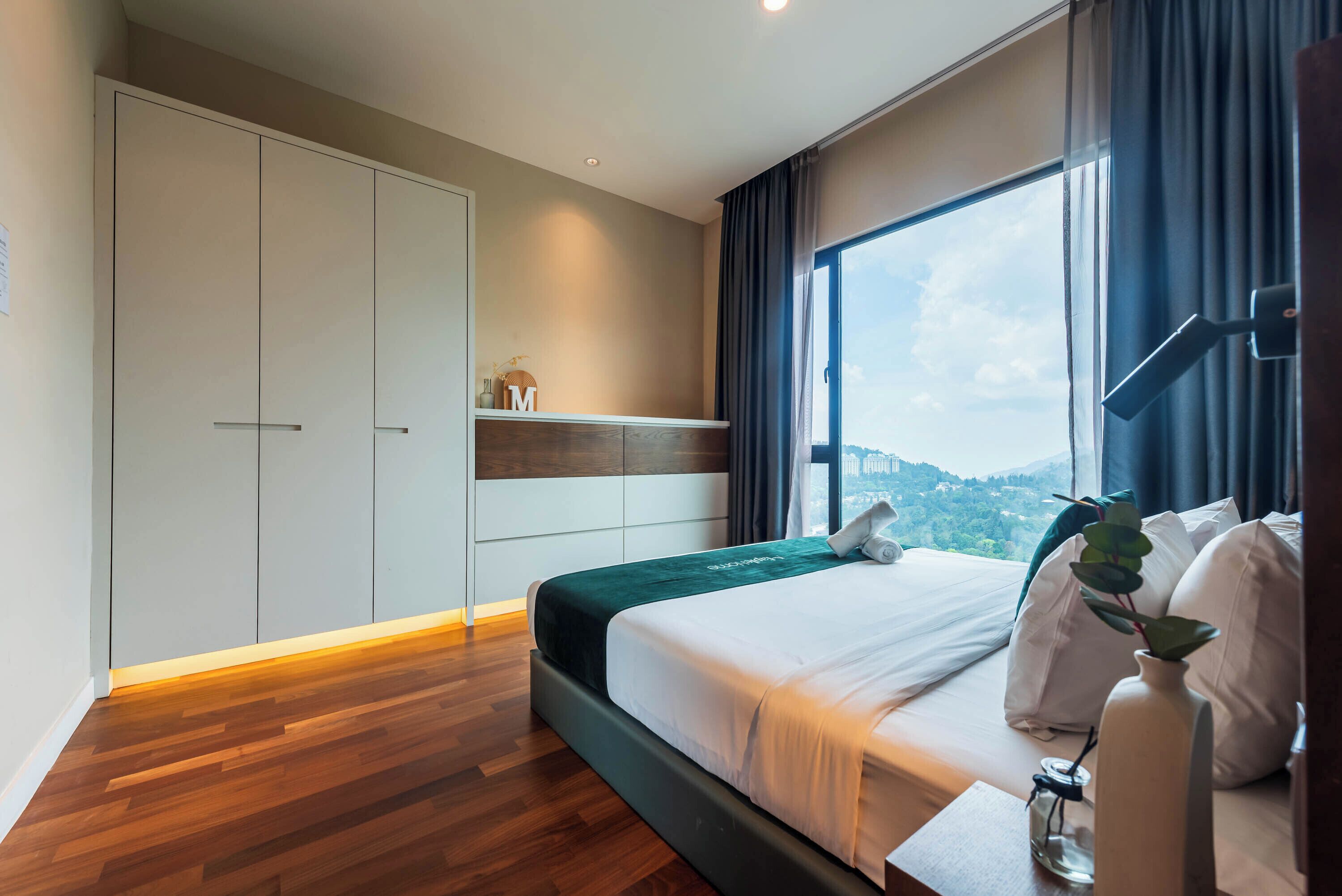 Quarto de hotel moderno com uma cama grande, um guarda-roupa, vista para a cidade e uma janela com cortinas.