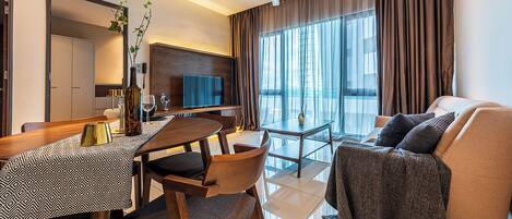 Quarto de hotel moderno com área de refeições, sofá e varanda com cortinas.