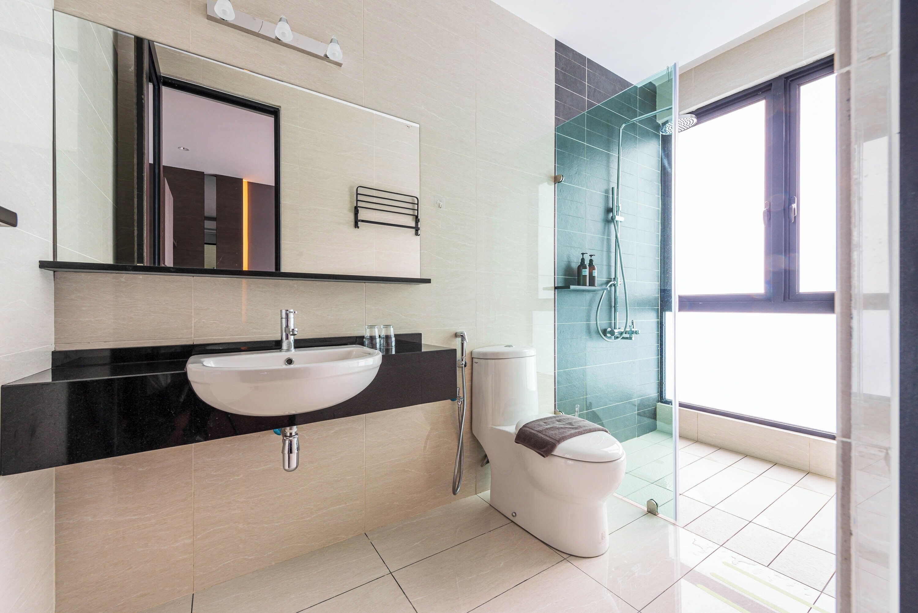 Une salle de bain moderne avec un grand miroir, un lavabo, des toilettes et un espace douche.