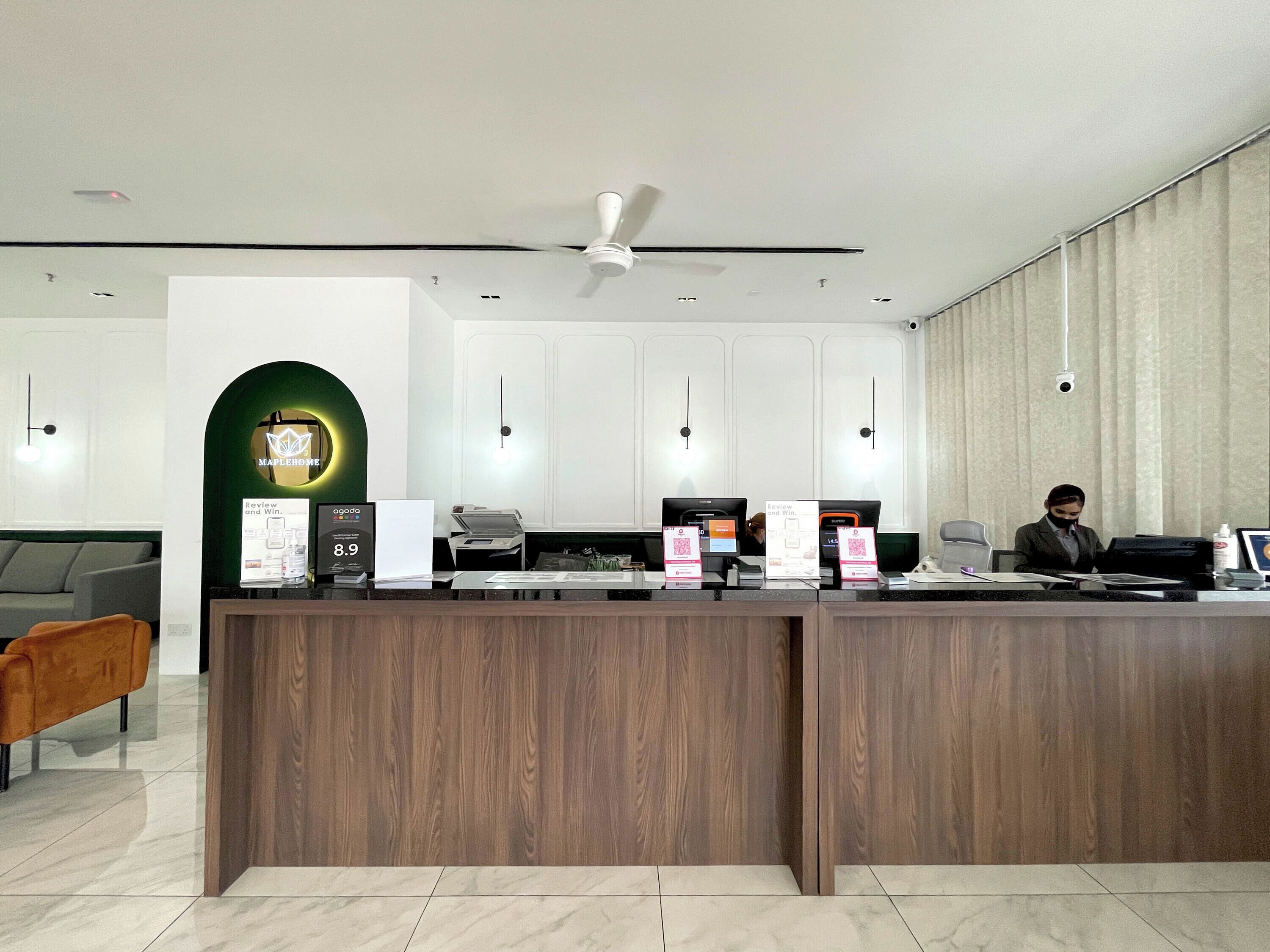 Un comptoir d’accueil au design moderne, une arche verte et un ventilateur de plafond.